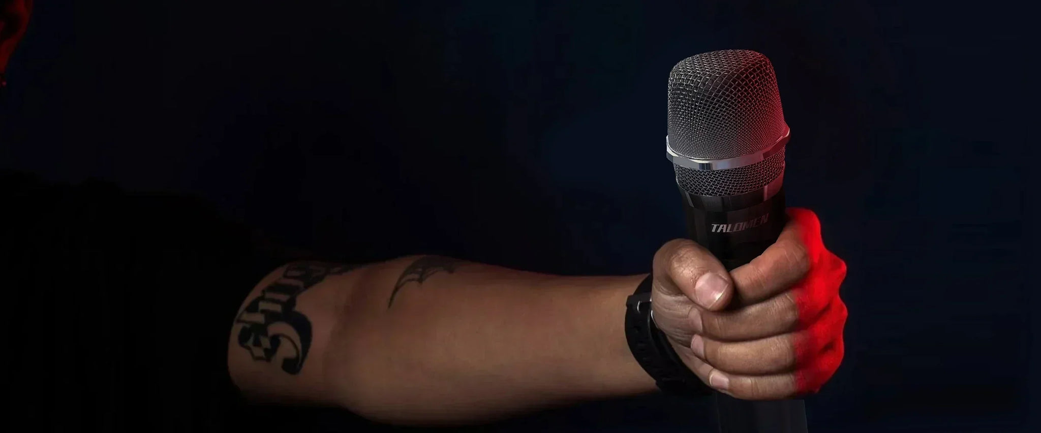 A close-up of a person's tattooed arm gripping a TALOMEN microphone against a dark background, with red lighting accentuating the hand and microphone.